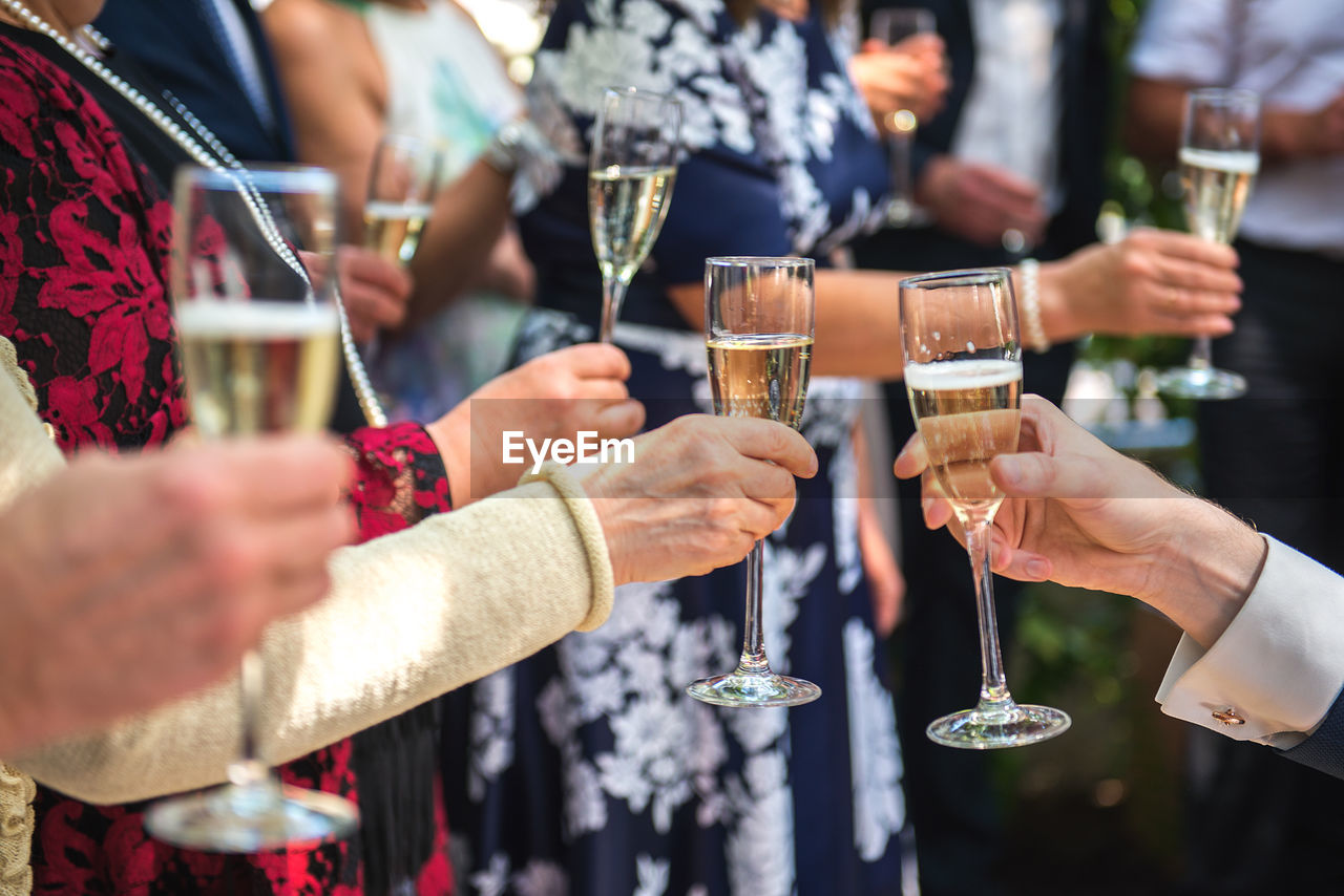 Cropped hands of friends toasting champagne flutes in party