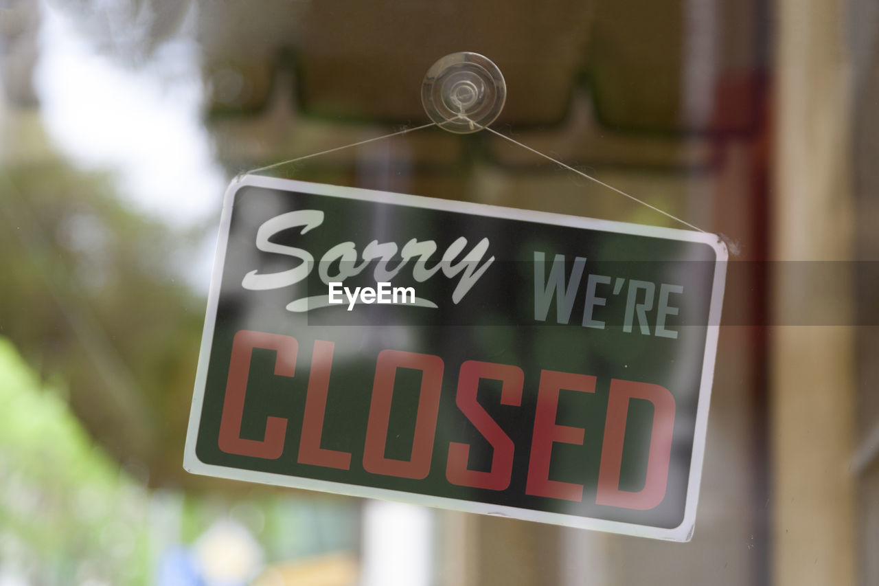 Close-up on an closed sign in the window of a shop saying sorry, we're closed.