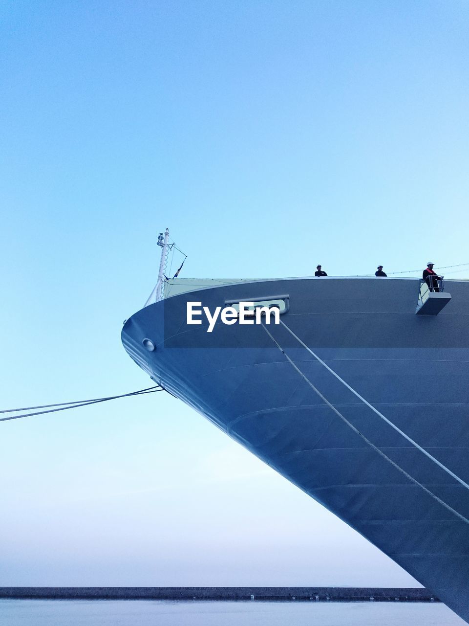 Low angle view of people working on ship in sea against sky