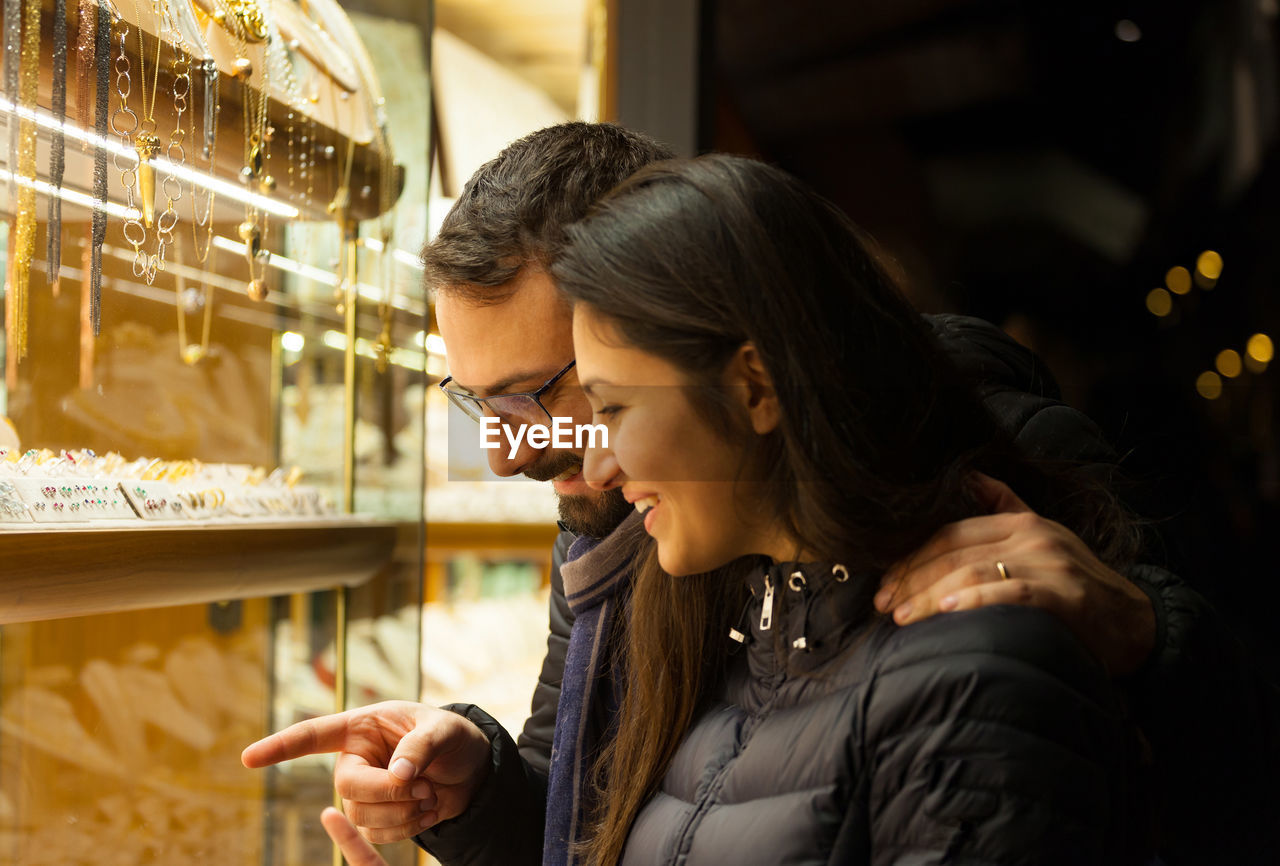 Smiling couple standing at jewelry shop at night