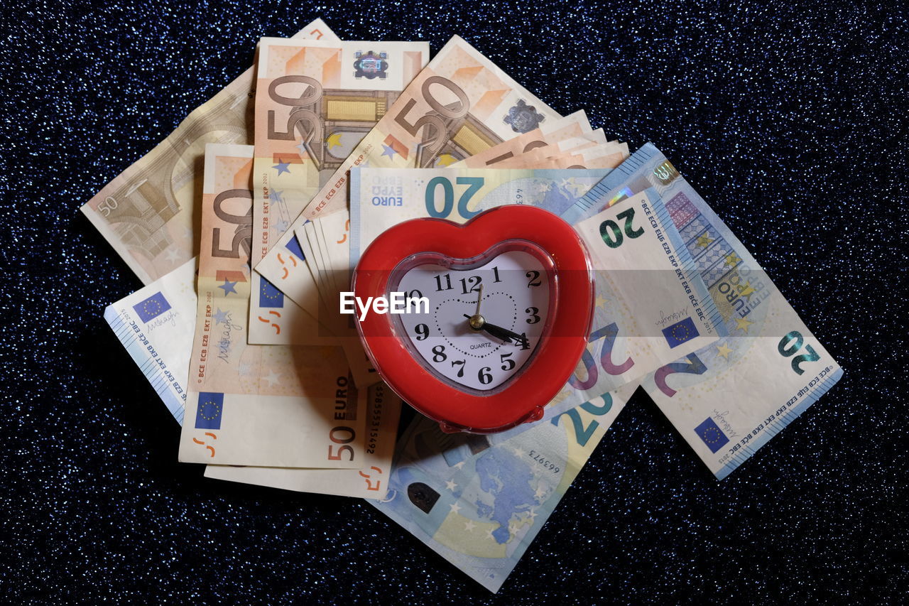 Directly above shot of alarm clock on european union currencies at table
