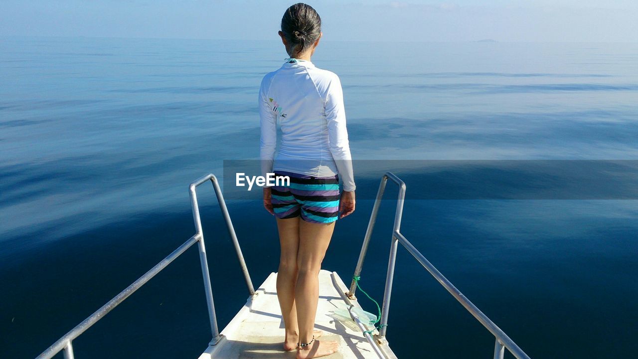 Full length rear view of woman standing on diving platform