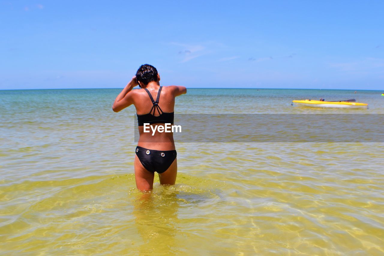 Rear view of woman in sea against blue sky
