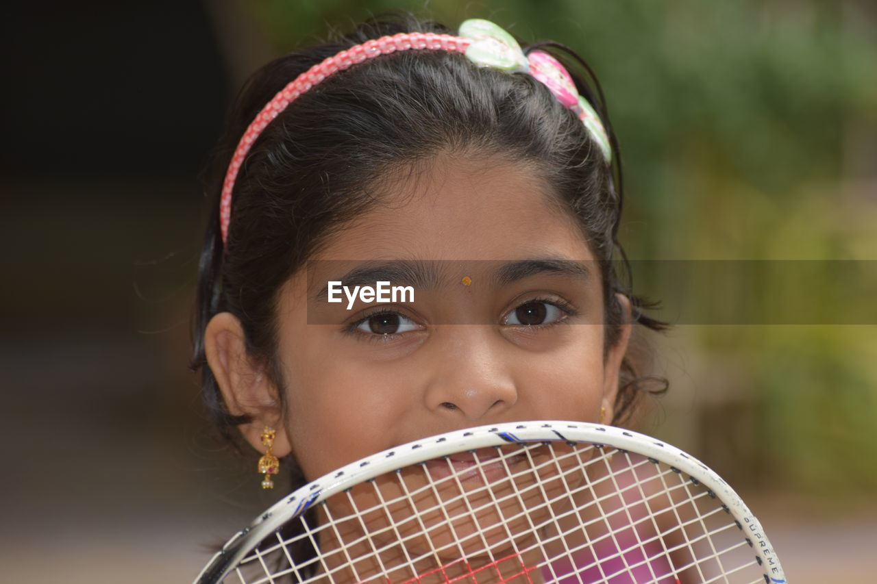 Close-up portrait of girl with badminton racket