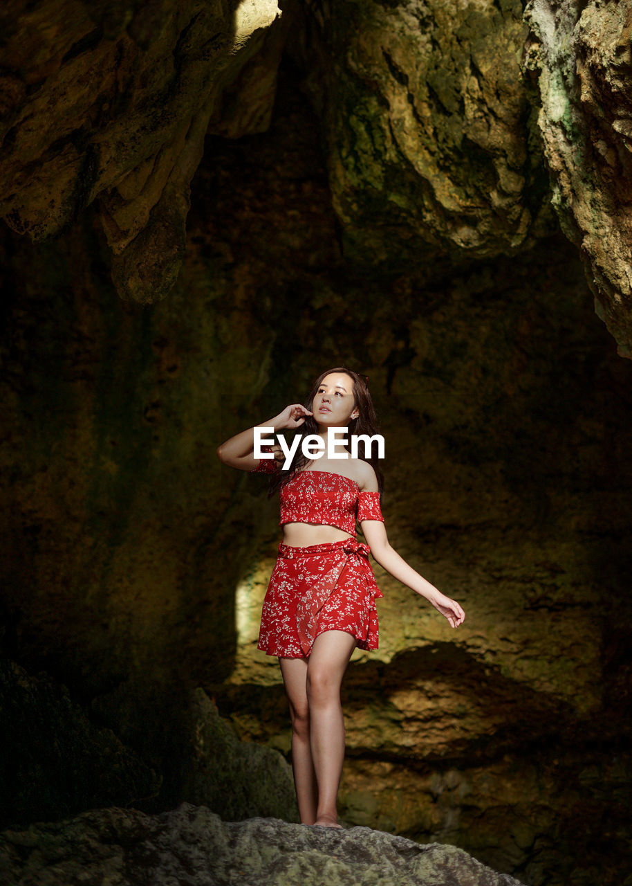 Full length of woman standing on rocky cave