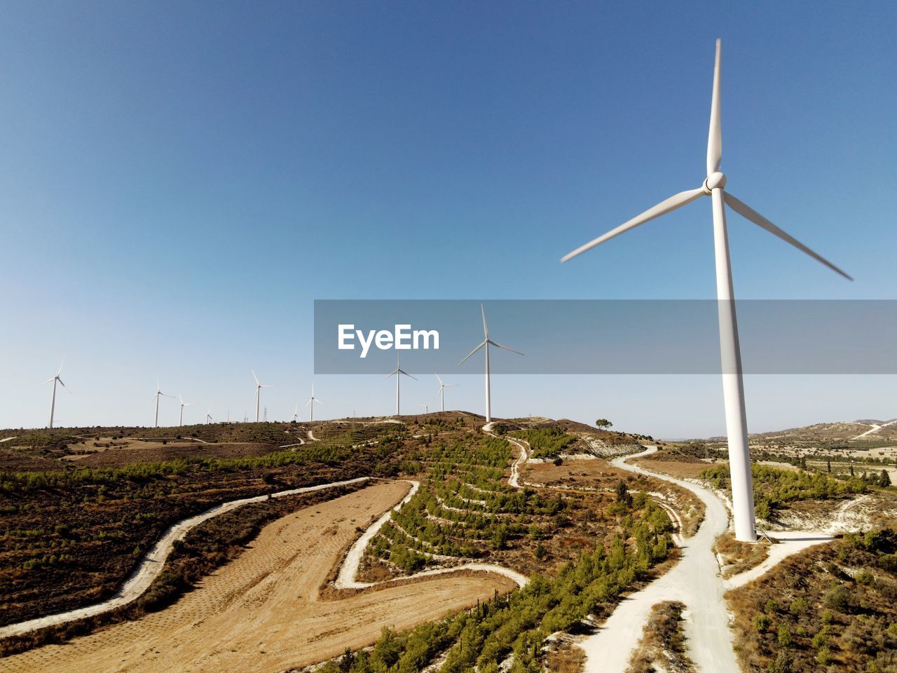 High angle view of road amidst land against sky, and windmills for electricity generation