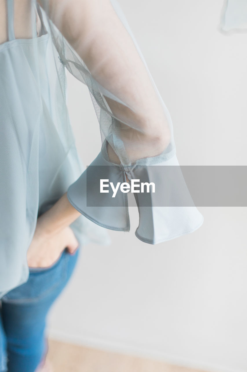 LOW SECTION OF WOMAN WITH LEGS ON WHITE BACKGROUND