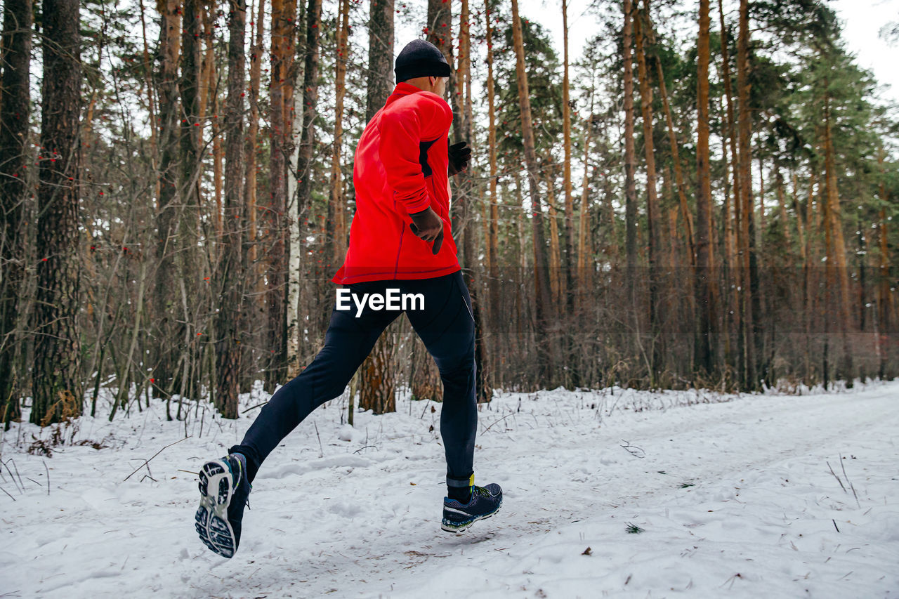 Male runner running winter marathon in forest