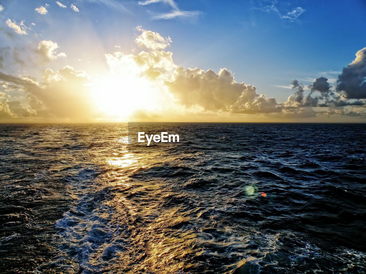 Scenic view of sea against cloudy sky on sunny day