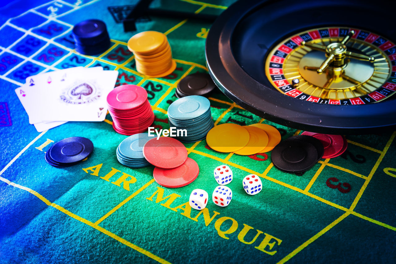 High angle view of gambling chips with cards and dice on table in casino
