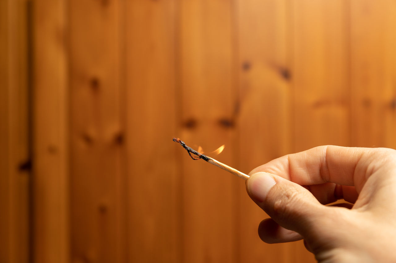 Person holds a matchstick by hands