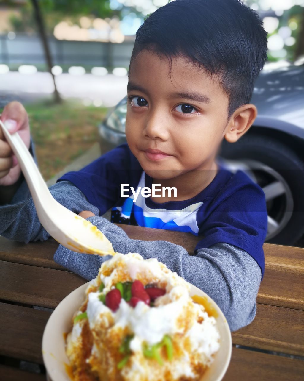 Portrait of boy eating food at table outdoors