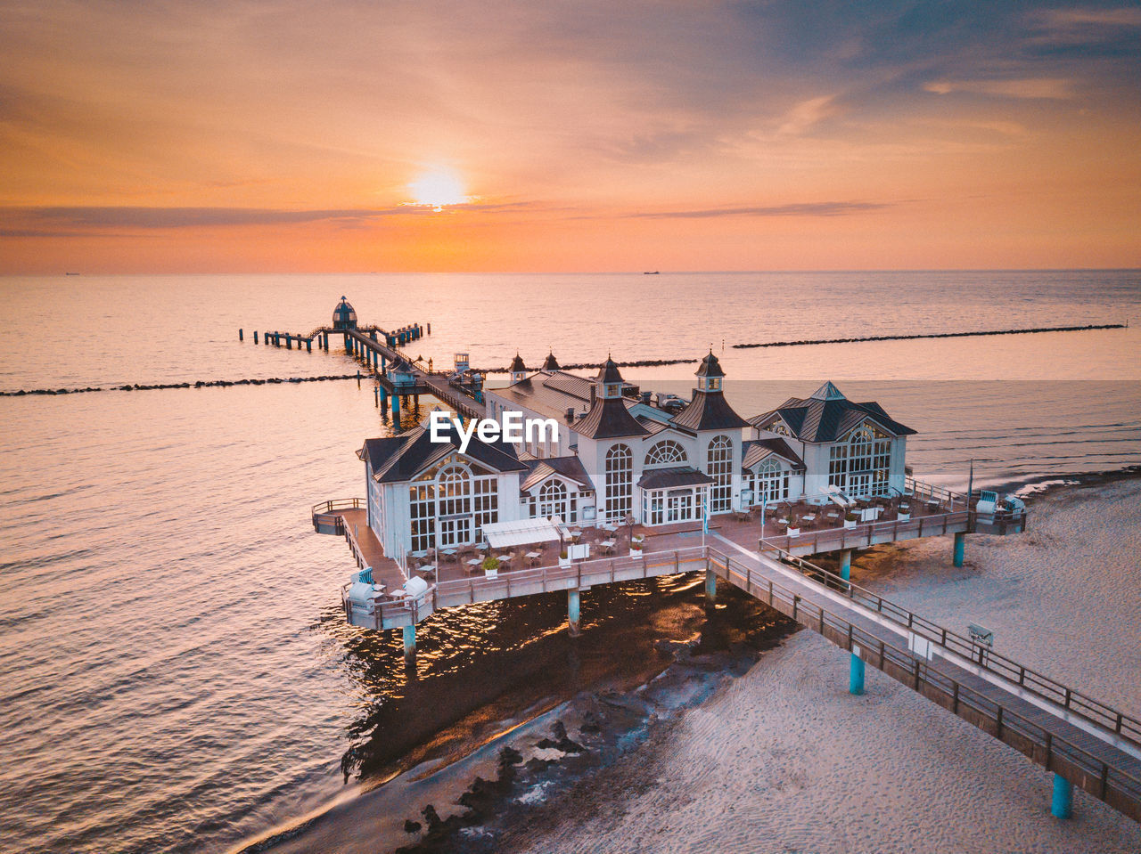 Drone view of stilt houses on pier over sea against sky during suset