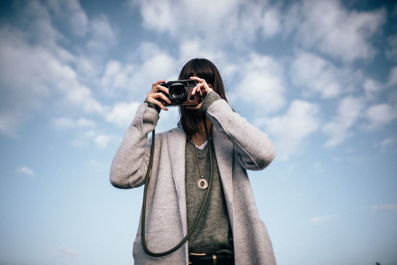 Woman photographing against sky | ID: 132376411