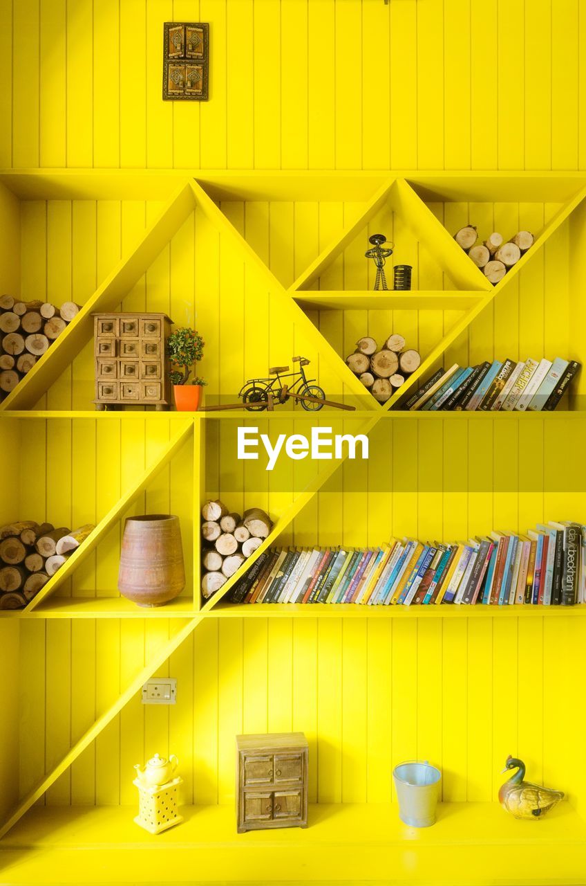 Books and logs arranged on yellow shelves at home