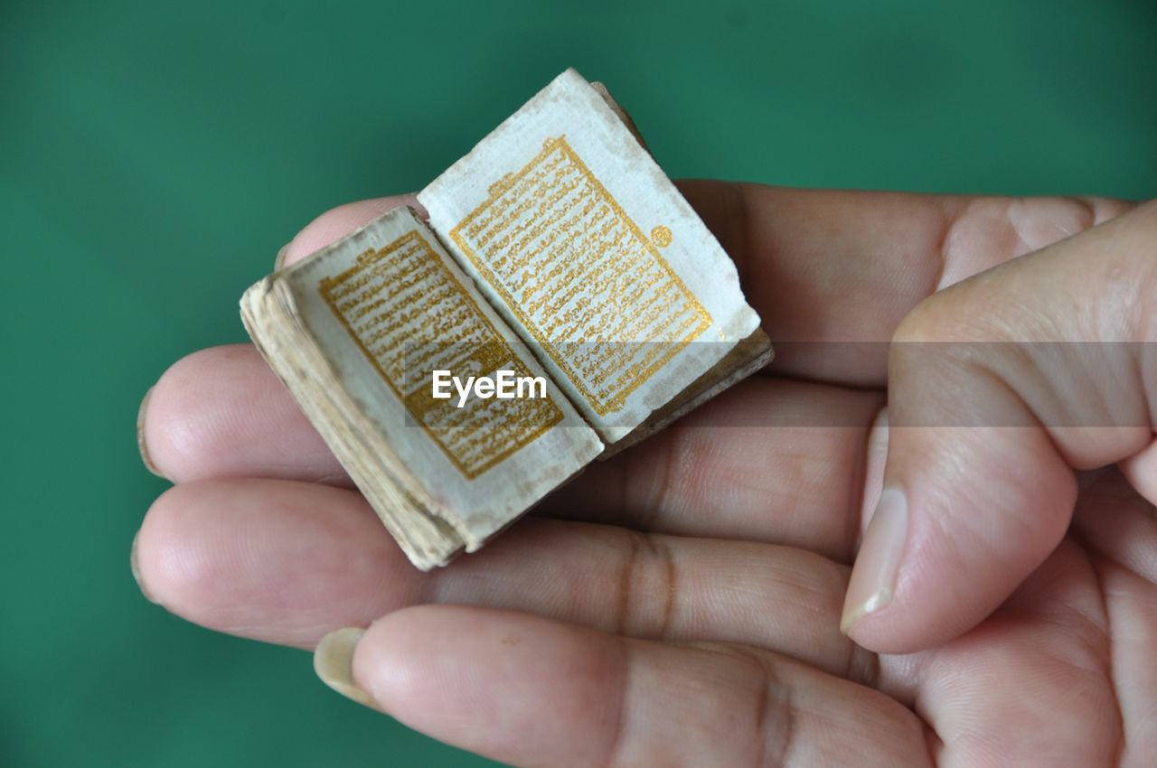 Close-up of hand holding small koran