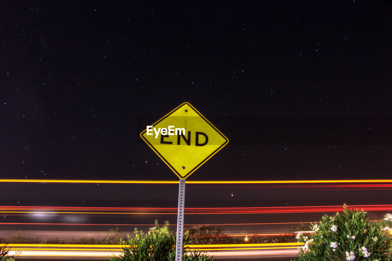 Road sign against light trails at night