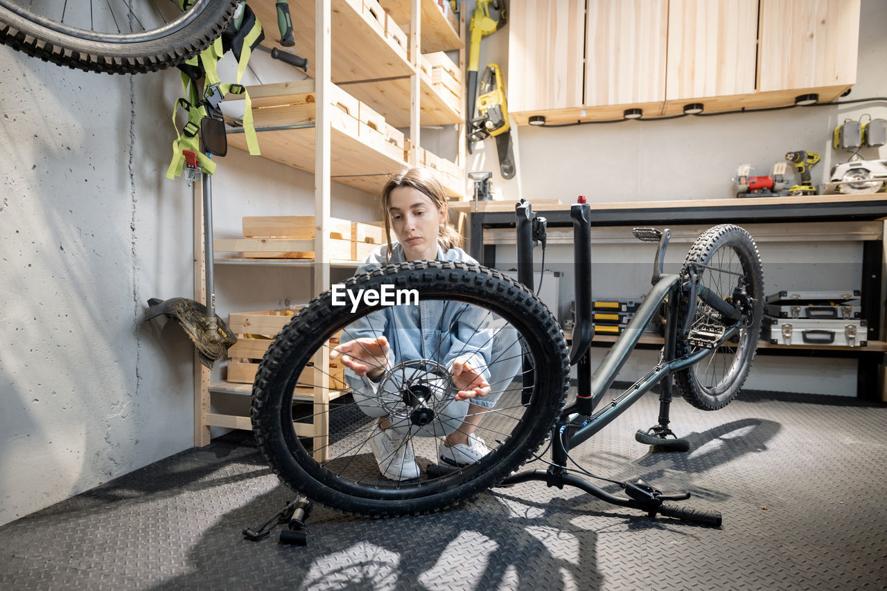 PORTRAIT OF YOUNG WOMAN WITH BICYCLE WHEEL IN SUBWAY