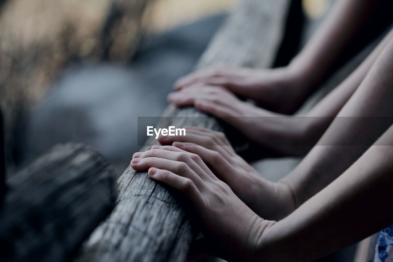 Cropped image of hands touching wooden railing