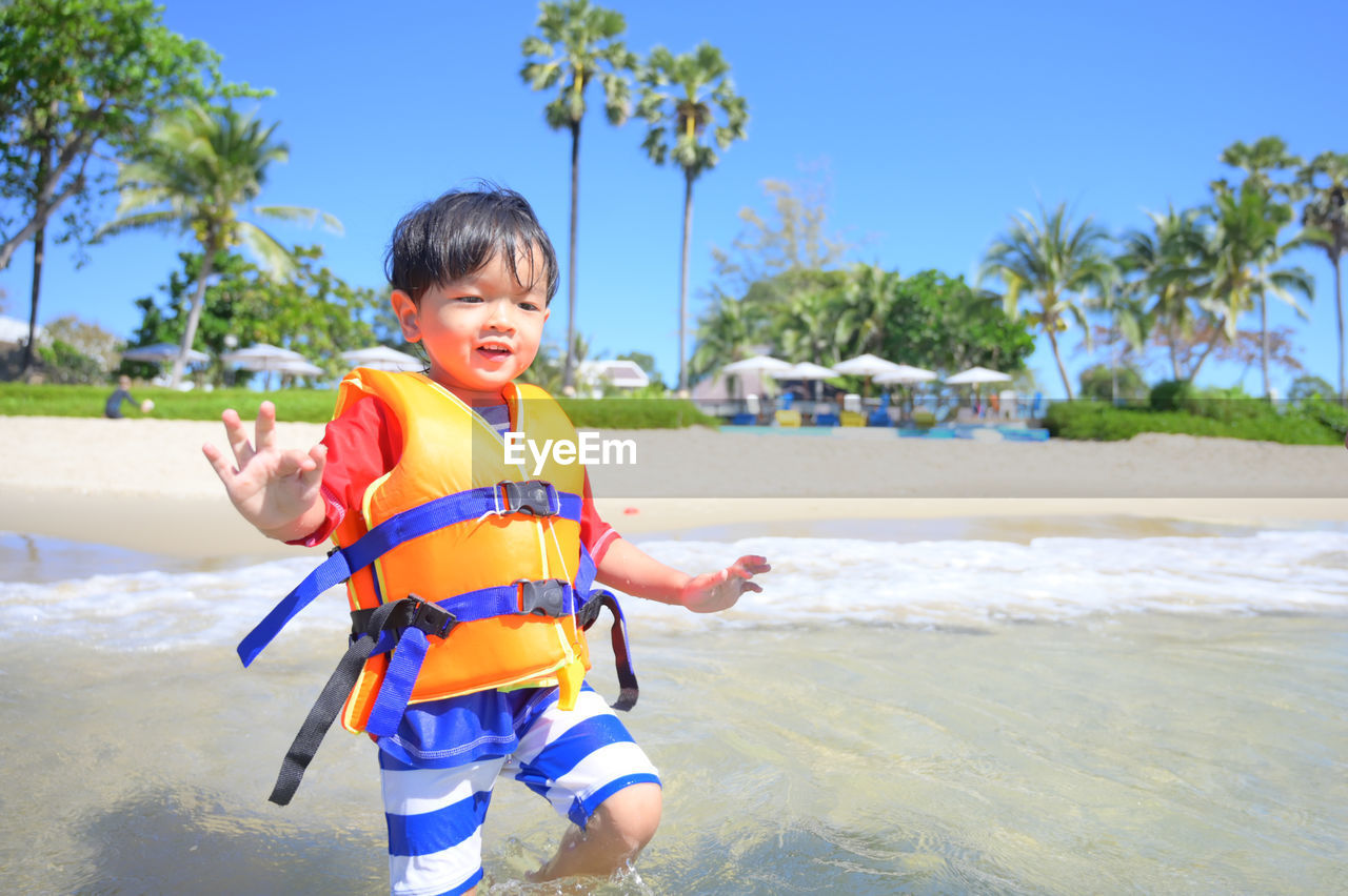 portrait of boy standing at beach against sky