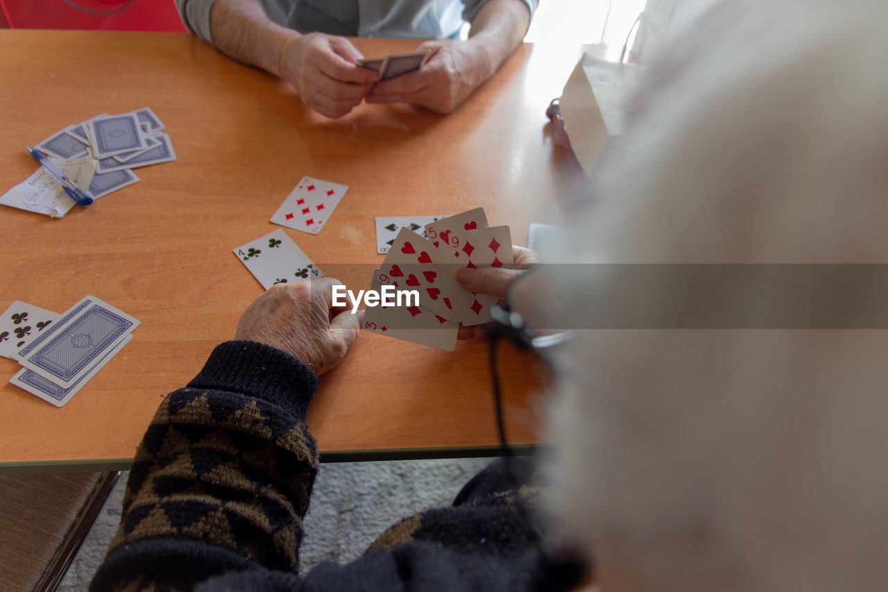 High angle view of people playing poker on table at home