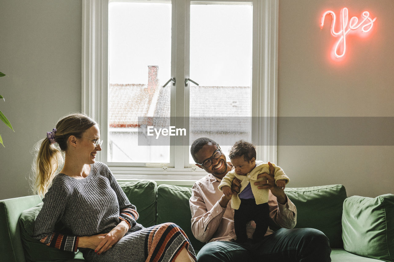 Parents with baby girl sitting on sofa