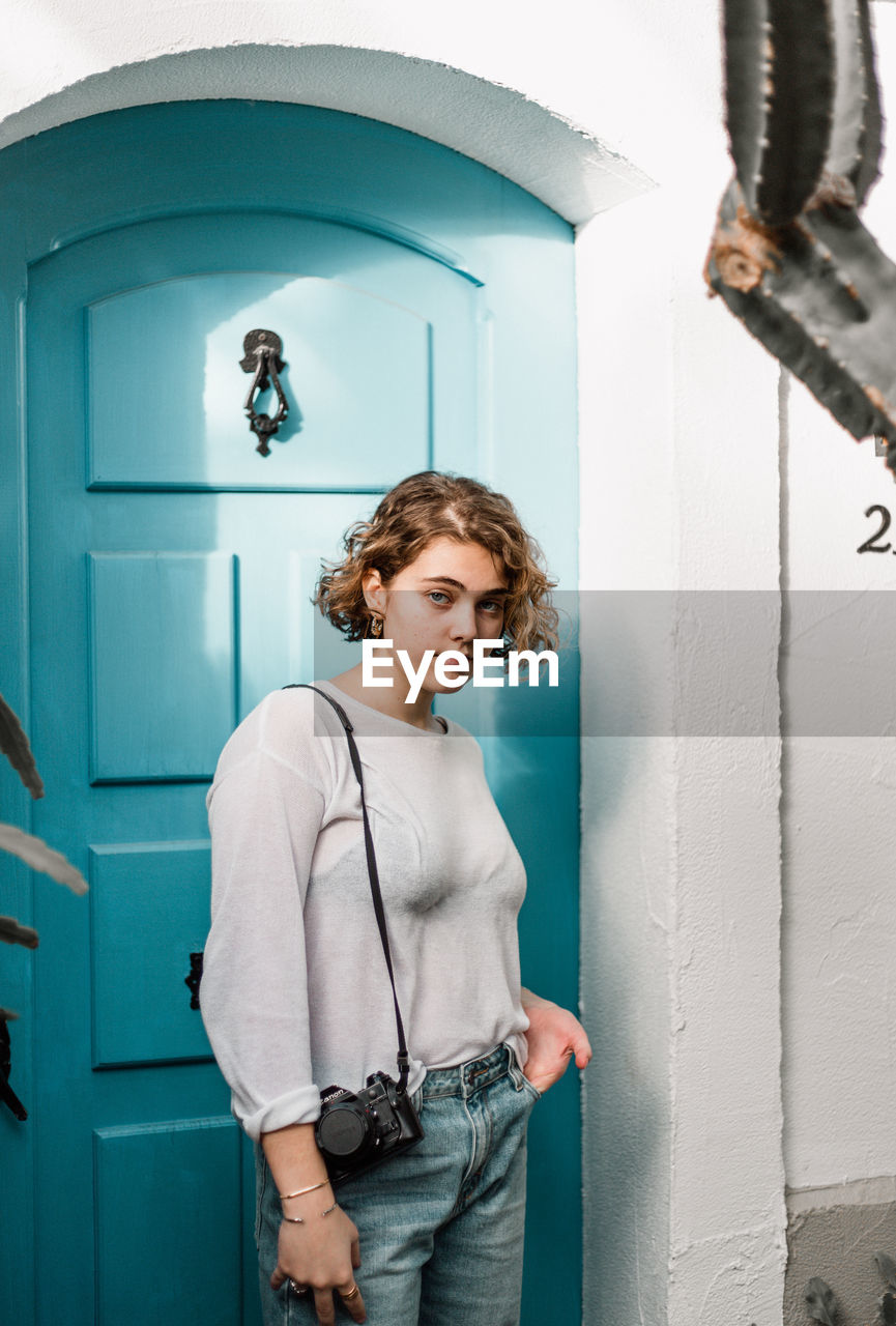 Portrait of young man standing against door