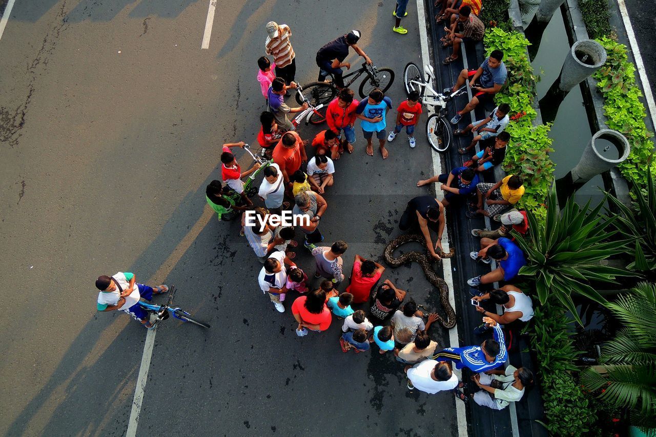 Snake charmer amidst people sitting on street