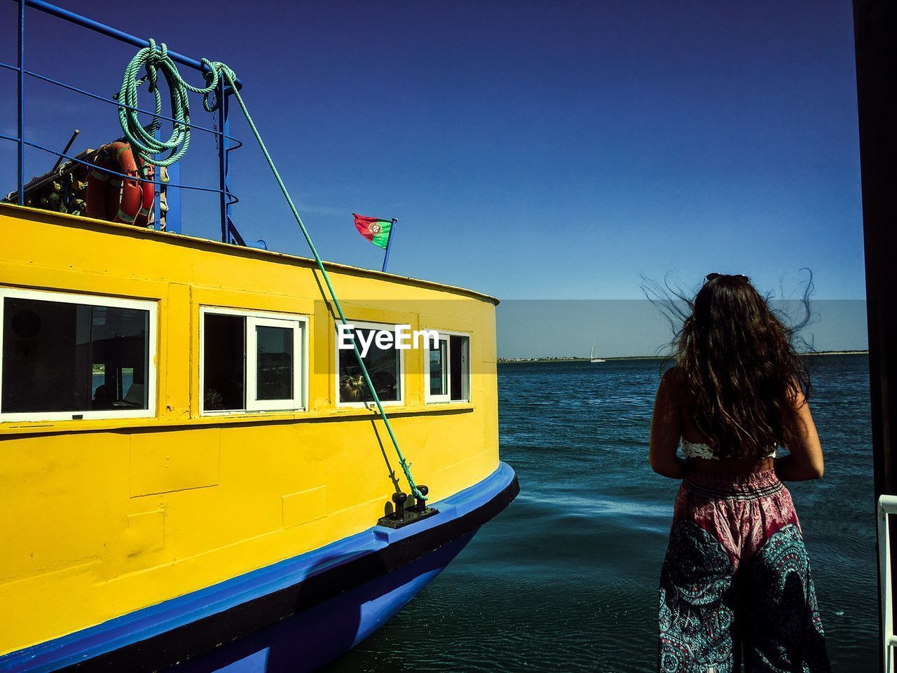 Rear view of teenage girl standing by boat against clear sky