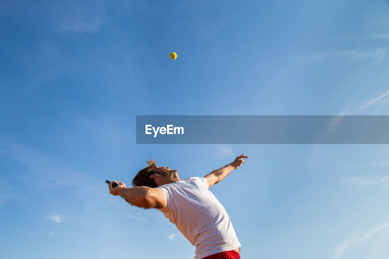 Low angle view of man playing tennis against sky