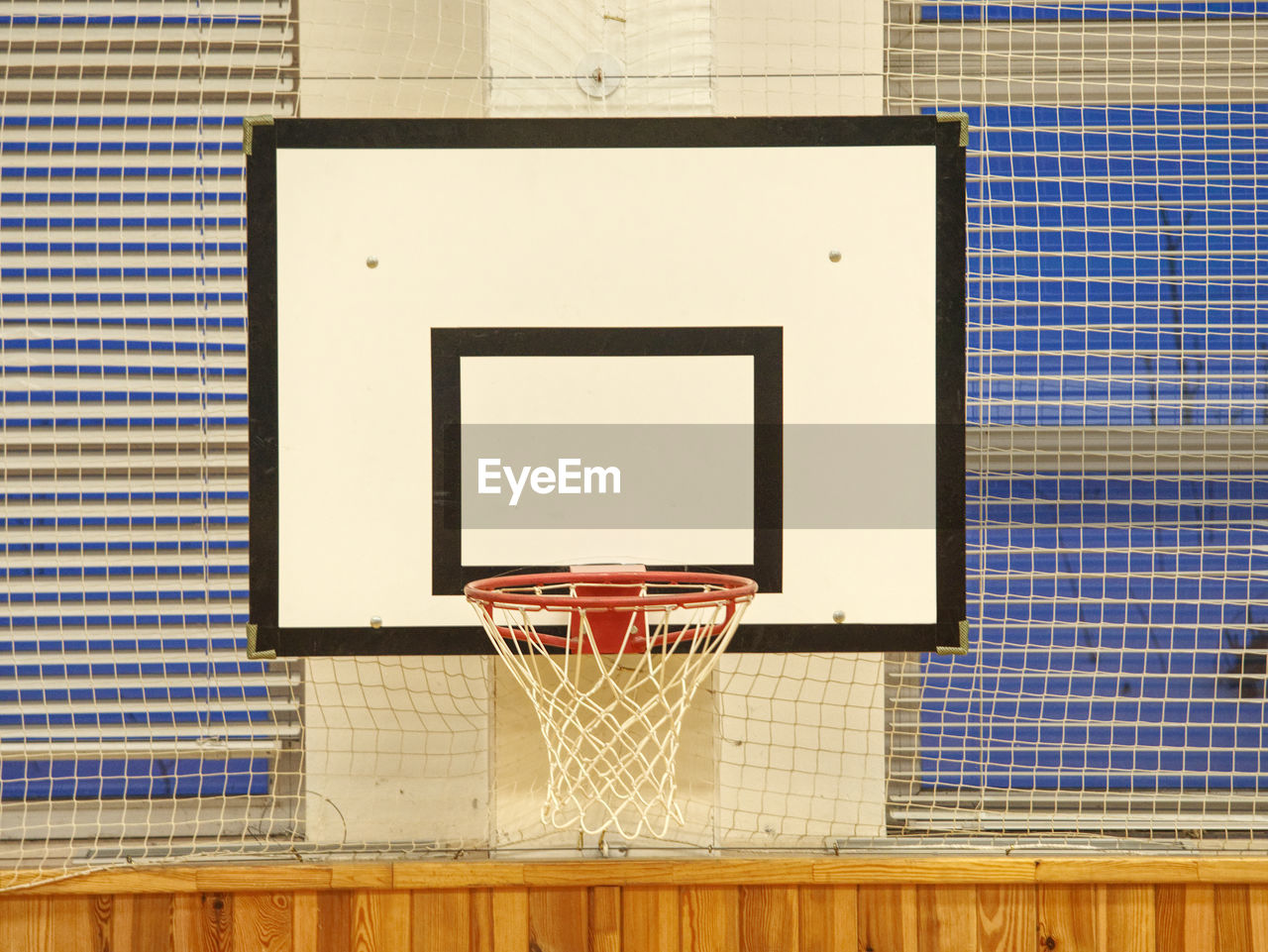 Basketball hoop in the high school gym. safety nets over windows. iluminated by fluorescent lighting