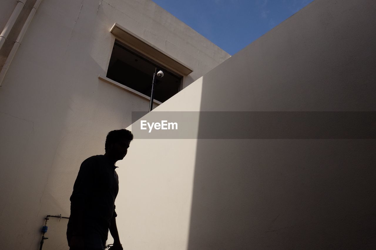 Low angle view of silhouette man against building