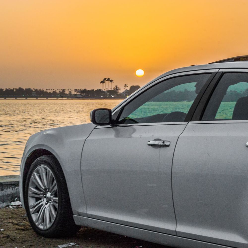Car parked on shore against orange sky