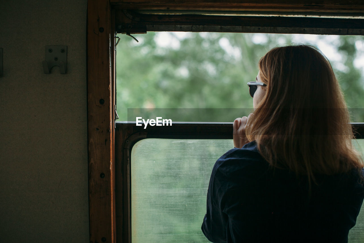 Rear view of woman looking through window in train