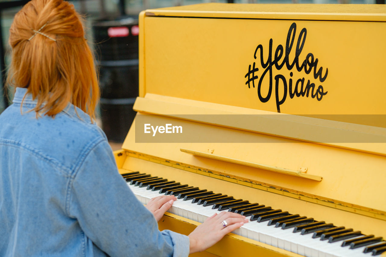 Rear view of woman playing piano outdoors