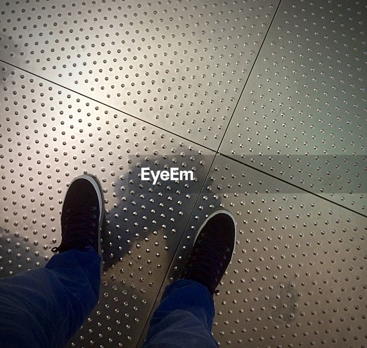 LOW SECTION OF PERSON STANDING ON TILED FLOOR