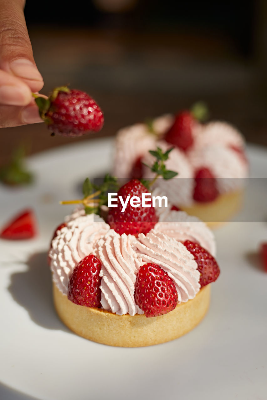 food and drink, food, hand, strawberry, fruit, berry, one person, freshness, healthy eating, dessert, sweet food, sweet, breakfast, holding, produce, sweetness, pavlova, meal, birthday cake, raspberry, adult, indoors, cake, plant, baked, strawberry pie, close-up, dish, lifestyles, icing, focus on foreground