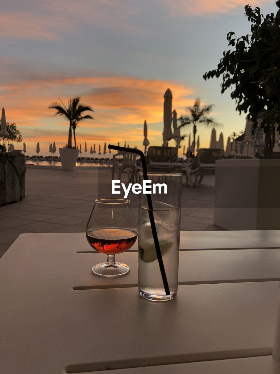 VIEW OF WINE GLASSES ON TABLE AGAINST SUNSET