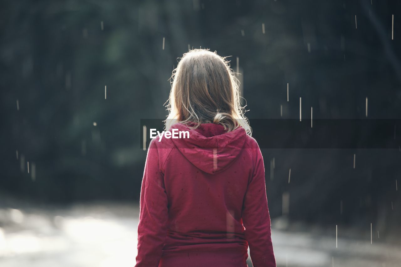 Rear view of girl standing in rain