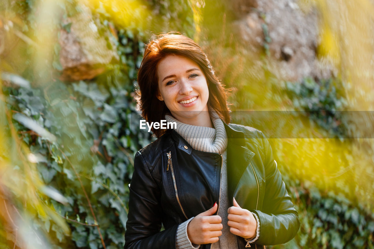 Beautiful young woman with light brown hair in a gray sweater and black leather