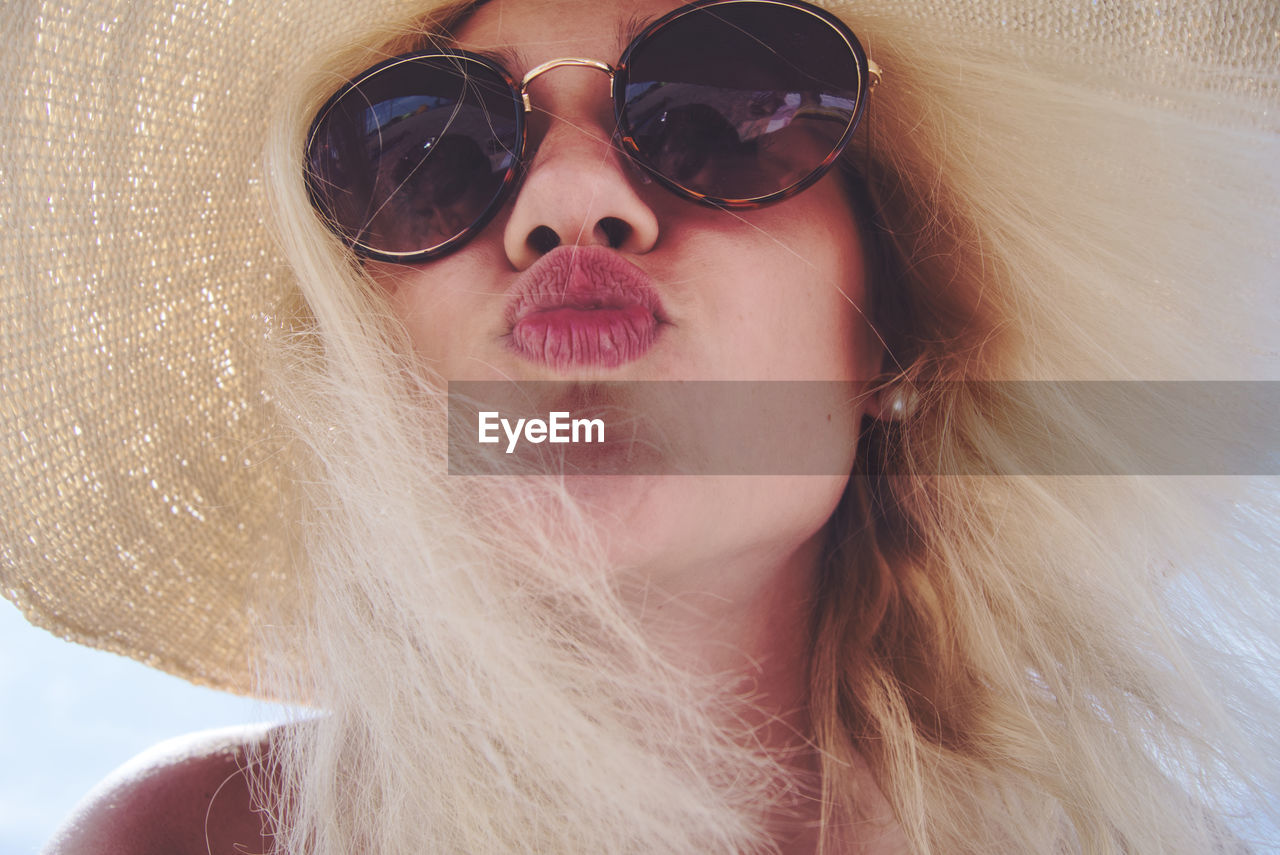 Close-up portrait of woman wearing sunglasses while puckering lips
