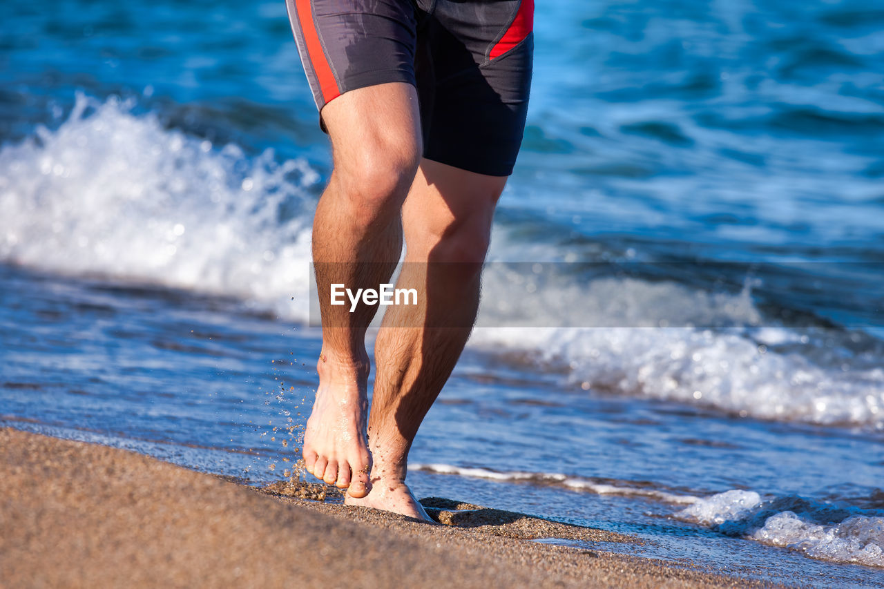 Low section of man running on beach