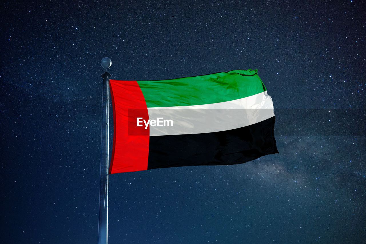 Low angle view of united arab emirates flag against star field sky