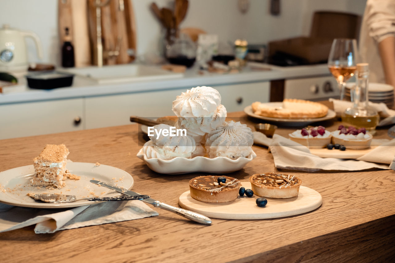 White airy meringue cake and round brown cake with nuts and caramel on the festive table