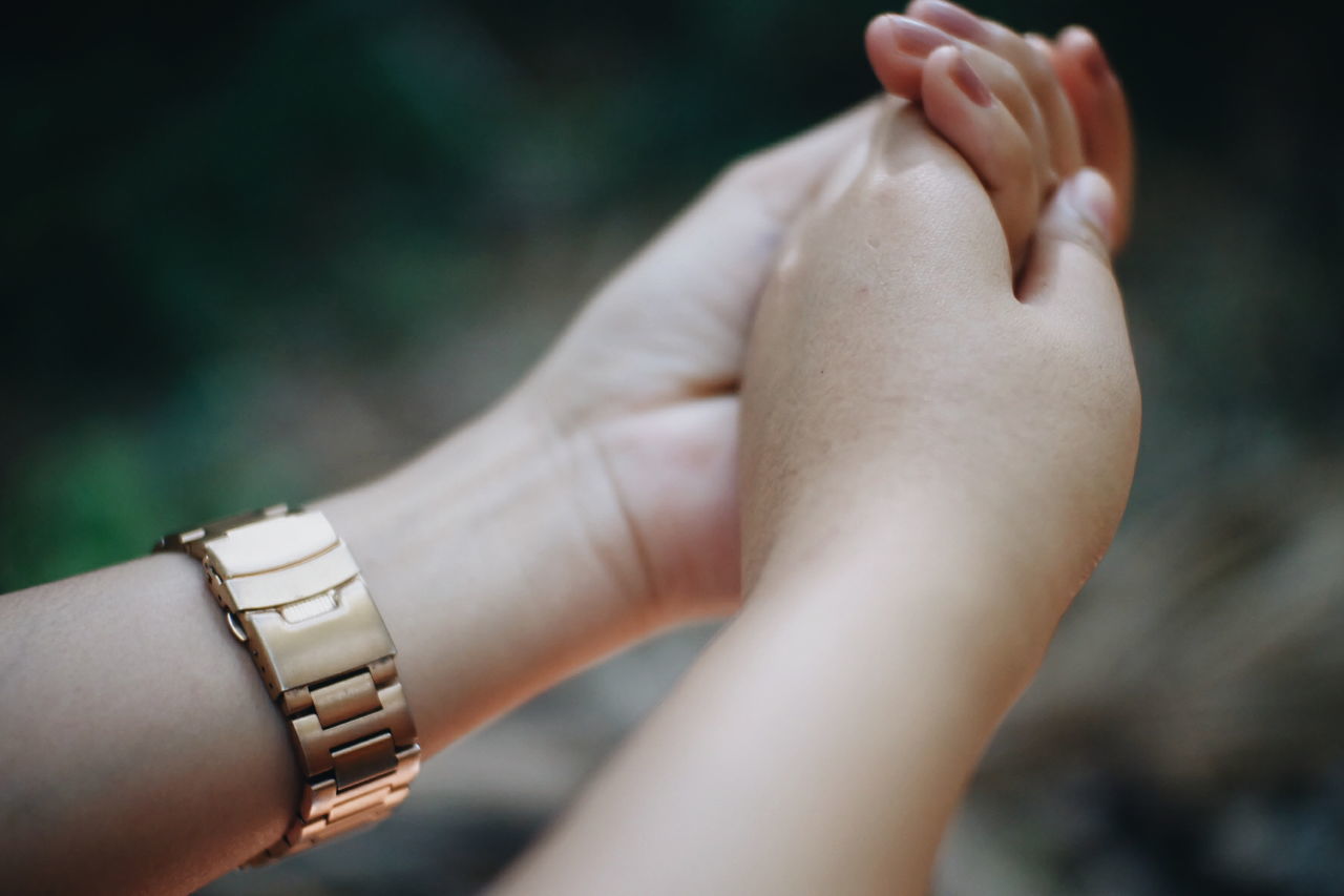 Cropped image of women holding hands outdoors