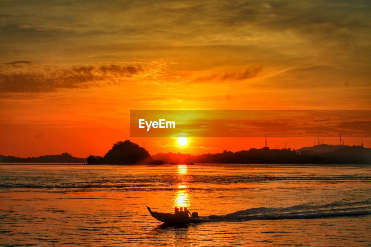 SILHOUETTE OF MAN IN BOAT ON SEA DURING SUNSET