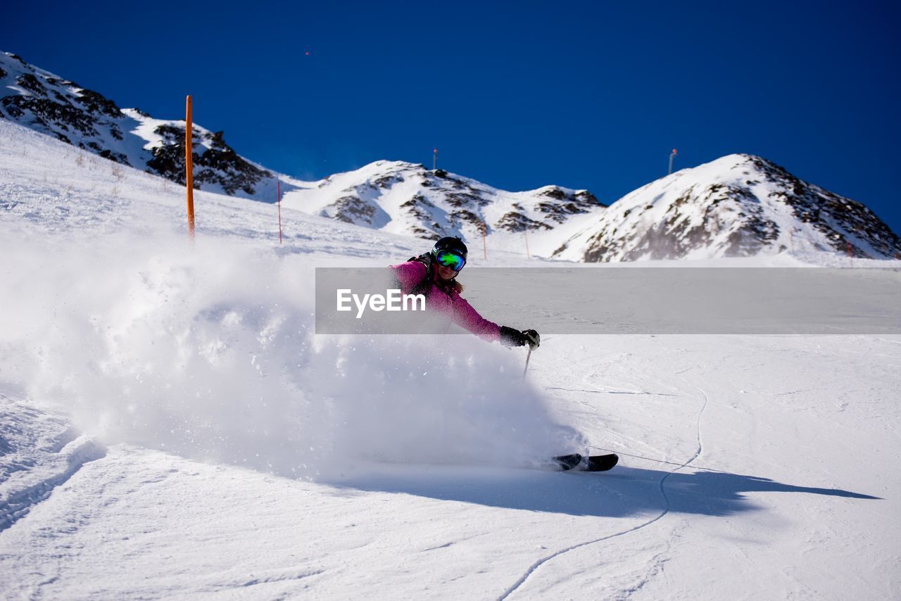 Woman skiing on snowy field against clear blue sky