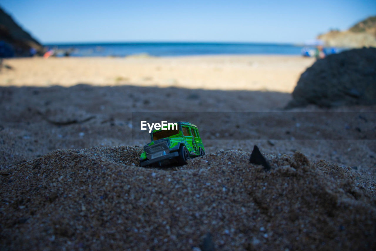 CLOSE-UP OF TOY CAR ON SHORE