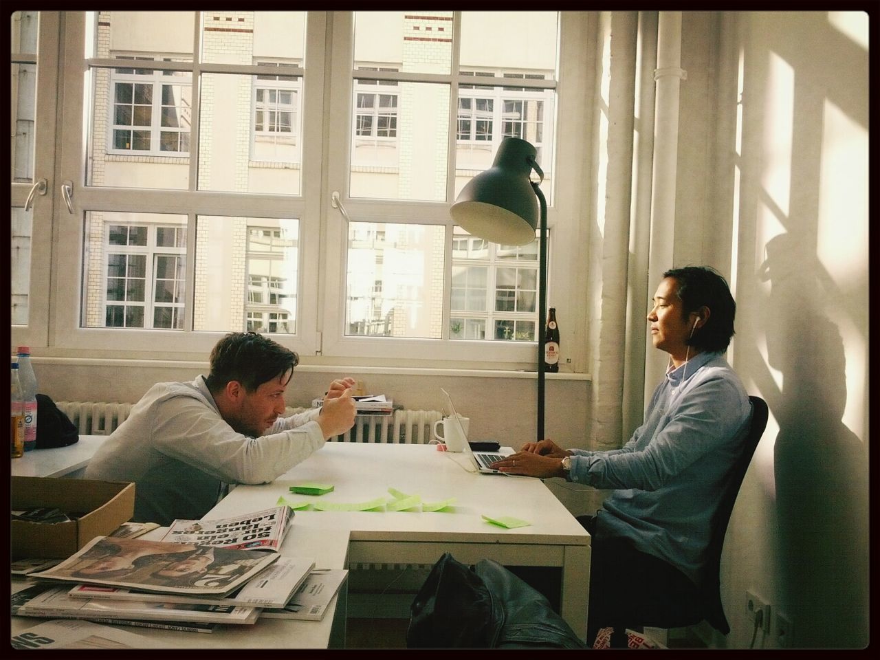 Side view of two young men working at desk in office