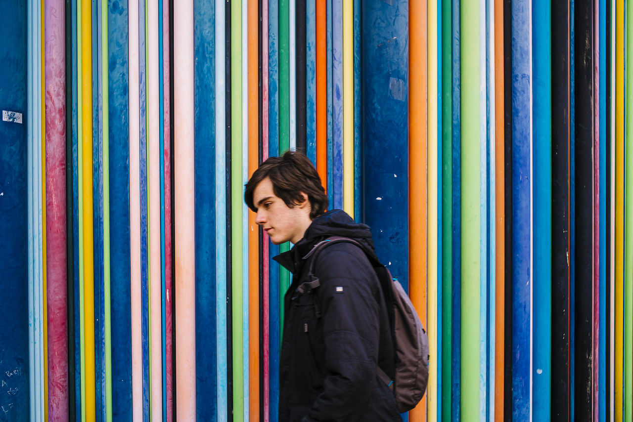 Handsome man walking against colorful wall